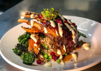 lamb chop over quinoa with broccoli, pomegranate and peas