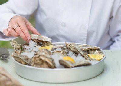 chef preparing raw oysters over ice with lemon wedges