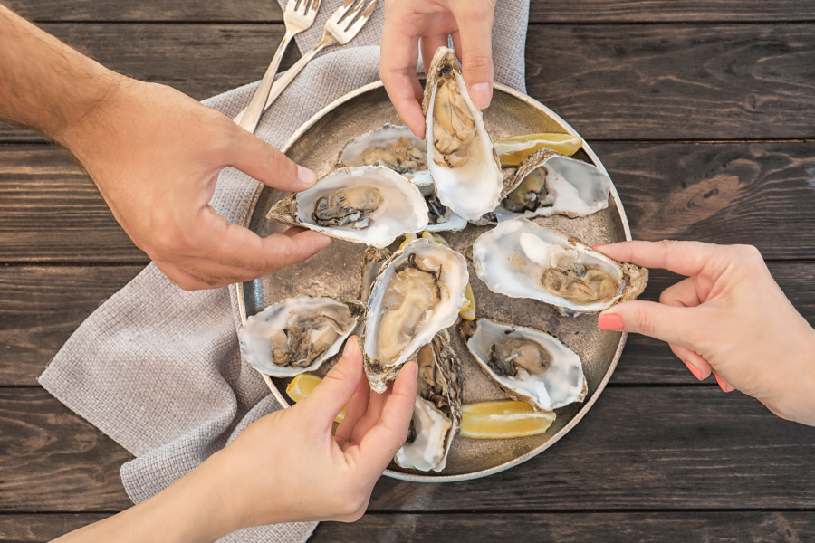 Feast-Bozeman-Health-Benefits-of-Oysters-Oceans-Superfood Group of friends enjoying a plate of fresh oysters
